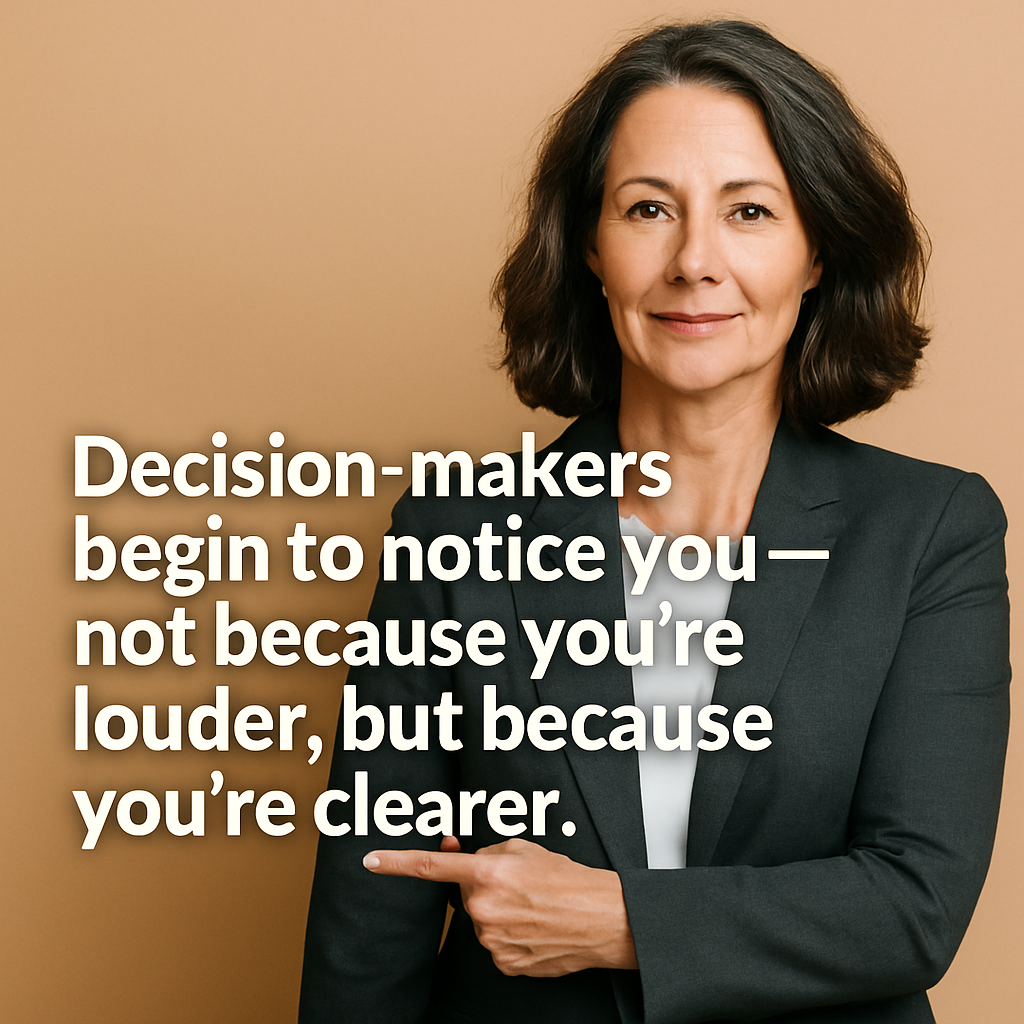 Professional middle-aged woman coach in a dark blazer pointing at bold white text overlay that reads, 'Decision-makers begin to notice you—not because you’re louder, but because you’re clearer,' against a beige background.